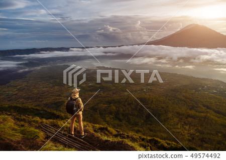 Man tourist looks at the sunrise on the volcano Batur on the island of Blai in Indonesia. Hiker man 49574492
