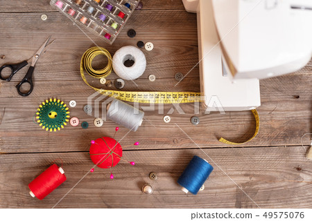 Seamstress or tailor background top view with sewing tools, colorful threads, sewing machine and Seamstress or tailor background top view with sewing tools, colorful threads, sewing machine and 49575076