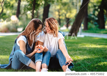 Candid friends seated at the park talking to each other. Candid friends seated at the park talking to each other. 49575802