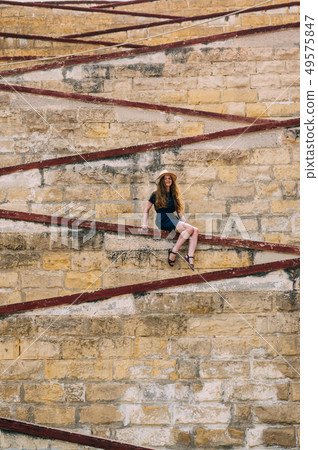 Young girl sitting on the city walls, old city 49575847
