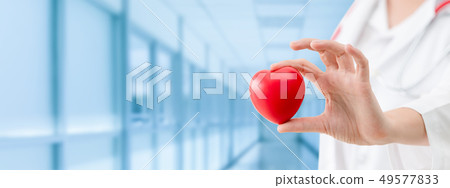 Doctor holding a red heart at hospital office. Doctor holding a red heart at hospital office. 49577833