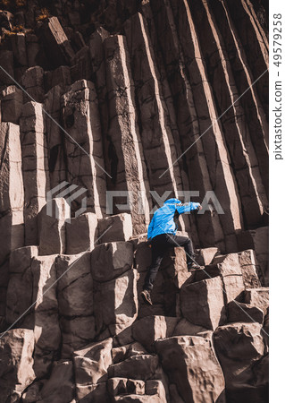 Traveler on hexagonal rocks in Vik, Iceland. 49579258