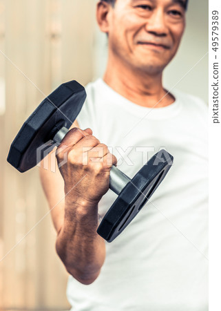 Senior man lifting dumbbell in fitness gym. 49579389