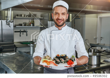 Already ready. Portrait of cheerful chef standing with cooked traditional japanese sushi Already ready. Portrait of cheerful chef standing with cooked traditional japanese sushi 49586302