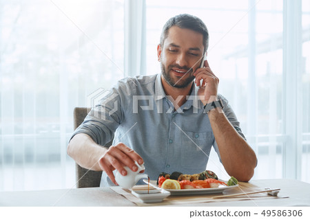 Work Hard. Think Hard. Eat Right. Smiling handsome businessman eating sushi Work Hard. Think Hard. Eat Right. Smiling handsome businessman eating sushi 49586306