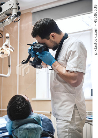 Your smile is our mission. Dentist with camera making shots of patient's smile after treatment 49586539