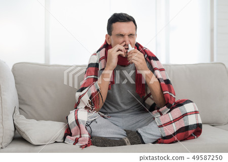 Man with Cold Sitting on Sofa in Checkered Blanket Man with Cold Sitting on Sofa in Checkered Blanket 49587250