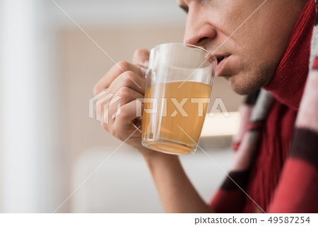 Man with Cold Sitting on Sofa in Checkered Blanket Man with Cold Sitting on Sofa in Checkered Blanket 49587254