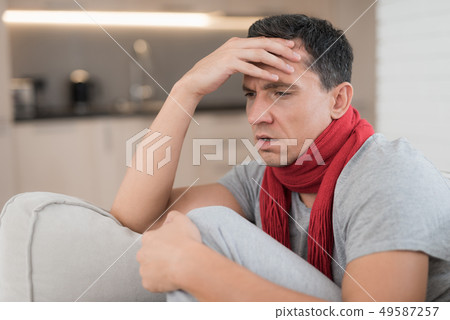 Man with Cold Sitting on Sofa in Red Scarf at Man with Cold Sitting on Sofa in Red Scarf at 49587257