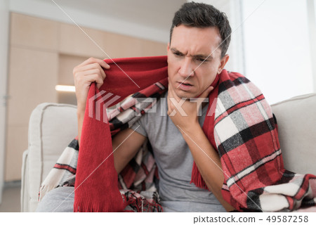 Man with Cold Sitting on Sofa in Checkered Blanket Man with Cold Sitting on Sofa in Checkered Blanket 49587258