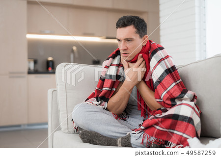 Man with Cold Sitting on Sofa in Checkered Blanket Man with Cold Sitting on Sofa in Checkered Blanket 49587259