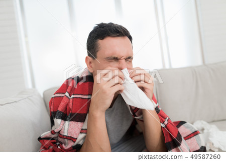 Man with Cold Sitting on Sofa in Checkered Blanket Man with Cold Sitting on Sofa in Checkered Blanket 49587260