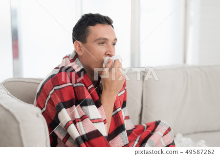 Man with Cold Sitting on Sofa in Checkered Blanket 49587262
