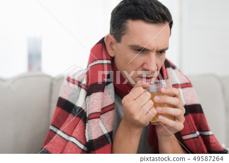 Man with Cold Sitting on Sofa in Checkered Blanket 49587264