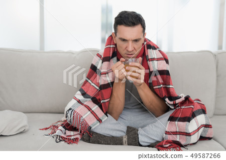 Man with Cold Sitting on Sofa in Checkered Blanket 49587266