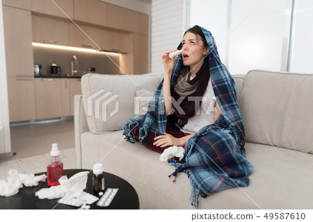 Upset Woman with Cold on Sofa in Scarf at Home. Upset Woman with Cold on Sofa in Scarf at Home. 49587610