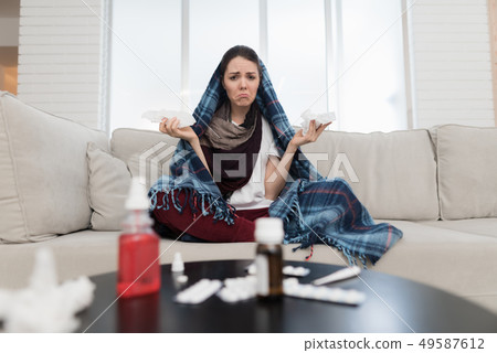 Upset Woman with Cold on Sofa in Scarf at Home. Upset Woman with Cold on Sofa in Scarf at Home. 49587612