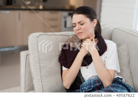 Upset Woman with Cold on Sofa in Scarf at Home. Upset Woman with Cold on Sofa in Scarf at Home. 49587622