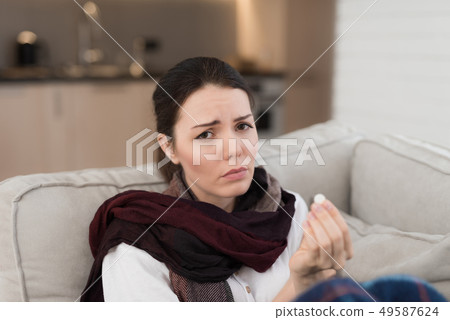 Upset Woman with Cold on Sofa in Scarf at Home. Upset Woman with Cold on Sofa in Scarf at Home. 49587624