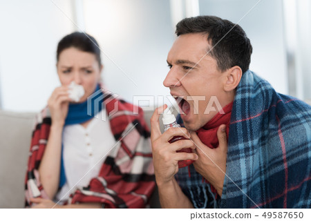 Sick Couple Sitting on Sofa in Checkered Blankets. 49587650
