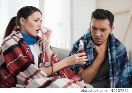 Sick Couple Sitting on Sofa in Checkered Blankets. Sick Couple Sitting on Sofa in Checkered Blankets. 49587651