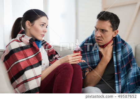 Sick Couple Sitting on Sofa in Checkered Blankets. Sick Couple Sitting on Sofa in Checkered Blankets. 49587652