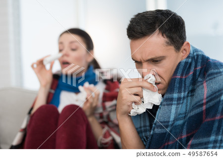 Sick Couple Sitting on Sofa in Checkered Blankets. Sick Couple Sitting on Sofa in Checkered Blankets. 49587654