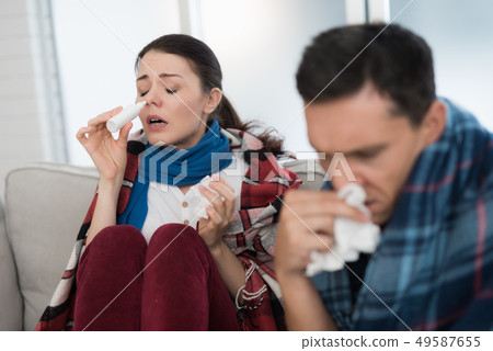 Sick Couple Sitting on Sofa in Checkered Blankets. Sick Couple Sitting on Sofa in Checkered Blankets. 49587655