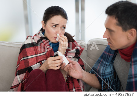 Sick Couple Sitting on Sofa in Checkered Blankets. Sick Couple Sitting on Sofa in Checkered Blankets. 49587657