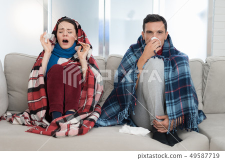 Sick Couple Sitting on Sofa in Checkered Blankets. Sick Couple Sitting on Sofa in Checkered Blankets. 49587719