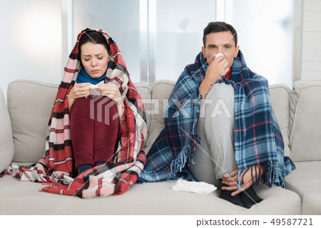 Sick Couple Sitting on Sofa in Checkered Blankets. Sick Couple Sitting on Sofa in Checkered Blankets. 49587721