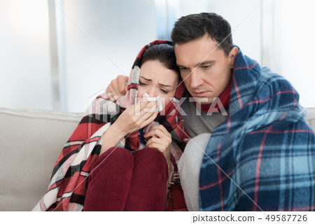 Sick Couple Sitting on Sofa in Checkered Blankets. Sick Couple Sitting on Sofa in Checkered Blankets. 49587726