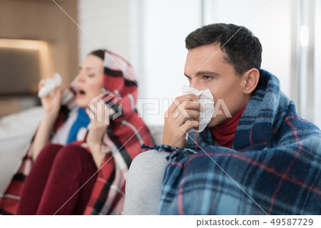 Sick Couple Sitting on Sofa in Checkered Blankets. Sick Couple Sitting on Sofa in Checkered Blankets. 49587729
