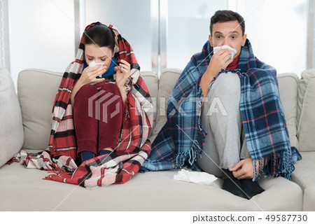 Sick Couple Sitting on Sofa in Checkered Blankets. Sick Couple Sitting on Sofa in Checkered Blankets. 49587730