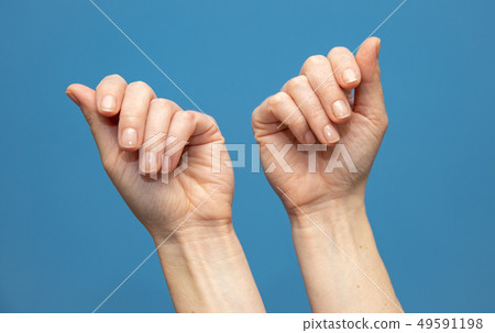 young woman showing hands on blue background. Attractive presentation of hands and nails young woman showing hands on blue background. Attractive presentation of hands and nails 49591198