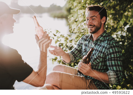 Smiling Men Drinking Beer near River in Summer. Smiling Men Drinking Beer near River in Summer. 49591622