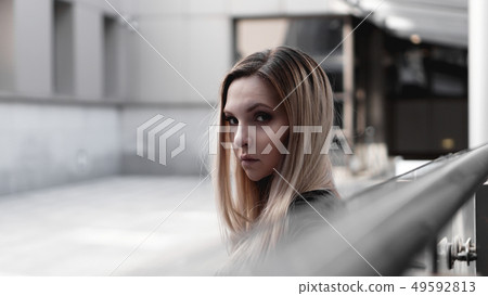 Urban style blonde girl with a stern look. Girl power and subculture concept. Urban style blonde girl with a stern look. Girl power and subculture concept. 49592813