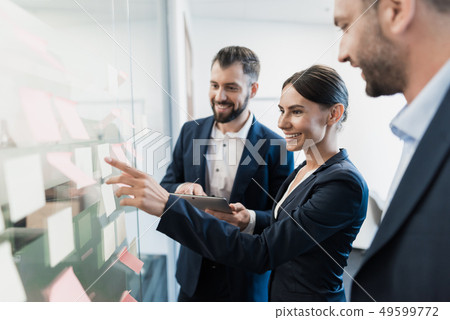 Two men and a woman in business suits check Two men and a woman in business suits check 49599772