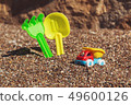 Children's toy truck with gravel or sand. Yellow scoop and green rake on the background. Concept of 49600126