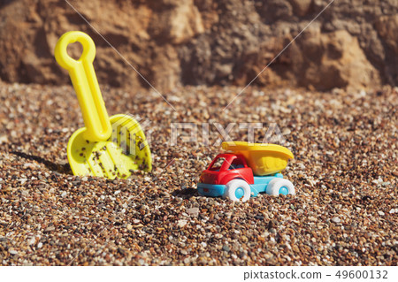 Children's toy truck with gravel or sand. Yellow scoop on the background. Concept of transportation Children's toy truck with gravel or sand. Yellow scoop on the background. Concept of transportation 49600132