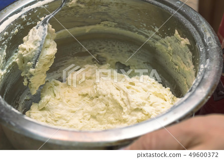 We knead the dough in a saucepan, spoon with dough 49600372