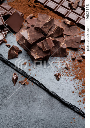 Dark or milk organic chocolate pieces on dark concrete backgound 49602138