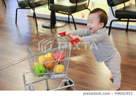A boy enjoying pushing a toy shopping cart A boy enjoying pushing a toy shopping cart 49602955