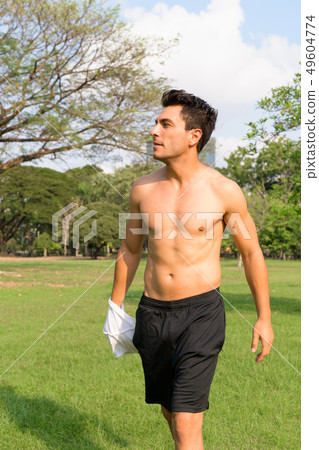 Profile view of young handsome shirtless Hispanic man at the park 49604774