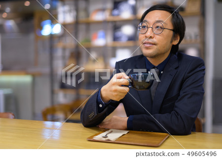 Happy Asian businessman thinking while drinking coffee 49605496