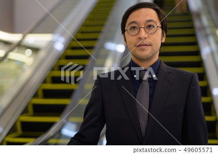 Asian businessman at escalator inside the office building Asian businessman at escalator inside the office building 49605571