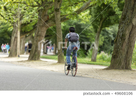 Man biking through the Amsterdam Vondelpark Man biking through the Amsterdam Vondelpark 49608106