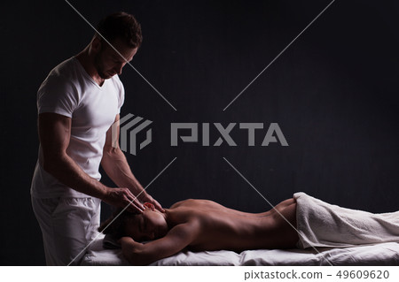 handsome masseur doing massage for brunette woman 49609620