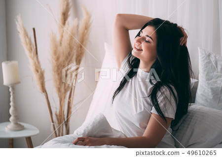 woman awakening stretching in bed in early morning woman awakening stretching in bed in early morning 49610265