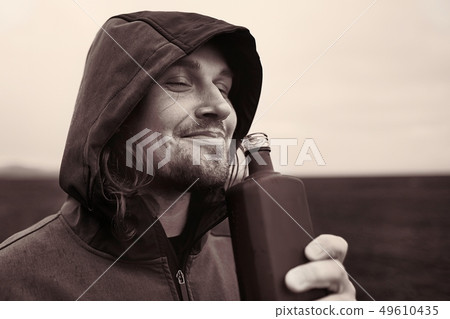 Hooded man drinking spirits in Iceland 49610435